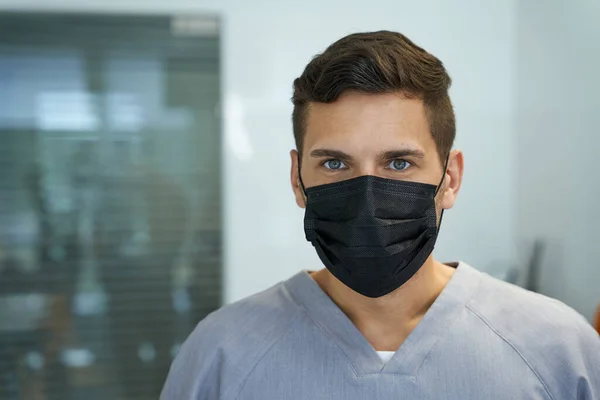 Ung manlig läkare bär mask och poserar för kameran — Stockfoto