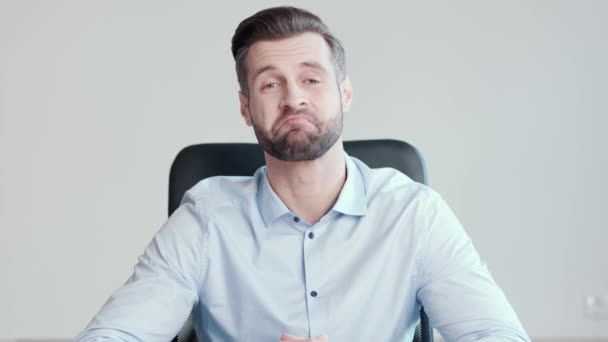 Erreichen einer Einigung. Schöner junger Mann, Büroangestellter, der dem Gesprächspartner aufmerksam zuhört, mit dem Kopf nickt und dann in die Kamera lacht, sitzt in seinem Büro — Stockvideo