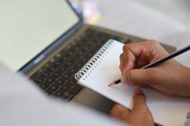 Kalem kullanan, ödevlerini yaparken not alan, dizüstü bilgisayarla evde oturan melez liseli kızların yakın plan fotoğraflarını çek.