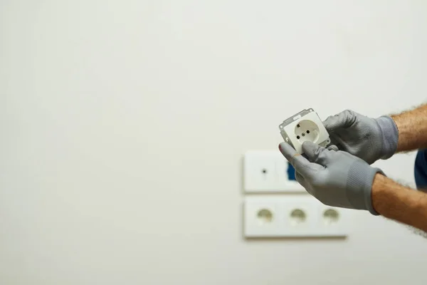 Nahaufnahme der Hände eines Elektrikers mit Schutzhandschuhen bei der Installation einer Steckdose in einem neuen Haus — Stockfoto