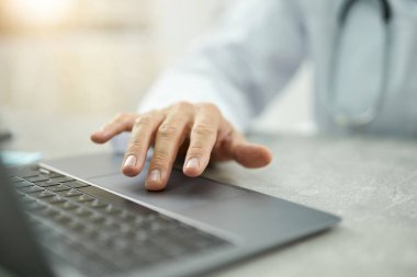 Klinikte modern dizüstü bilgisayar kullanan erkek doktor.