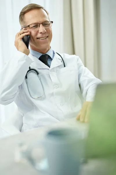 Médico alegre falando no telefone celular na clínica — Fotografia de Stock