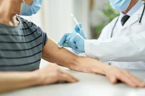 Läkare som rengör patientens arm med alkoholtork före injektion — Stockfoto