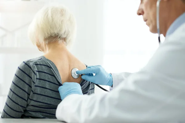 Läkare undersöker kvinnliga patienter med stetoskop på kliniken — Stockfoto