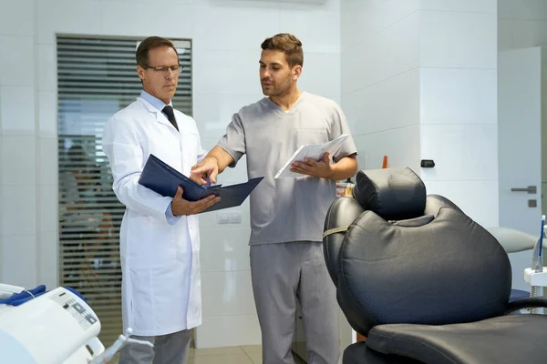 Diş kliniğinde evraklara bakan iki sağlık çalışanı. — Stok fotoğraf