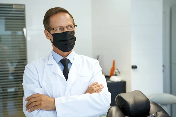Läkare i ansiktsmask tittar åt sidan — Stockfoto