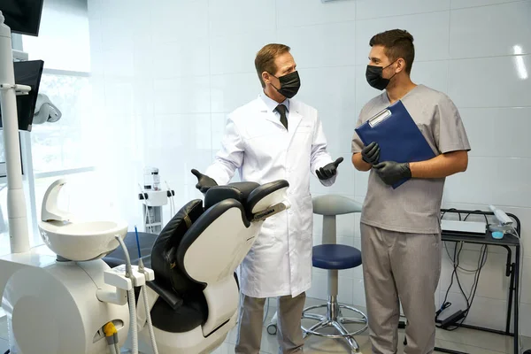 Diş kliniğinde çalışan maskeli ve eldivenli iki adam. — Stok fotoğraf