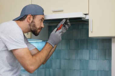 Hızlı ve profesyonelce. Kapalı alanda tornavidayla mutfak sökücüsünü tamir ederken dikkatli görünen genç bir tamirci.