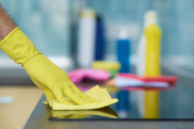 Kaliteli temizlik. Adamın yakın çekimi, profesyonel erkek temizlikçi mutfakta fırın temizlerken eldiven giyiyor.