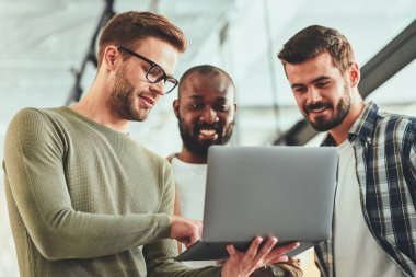 Genç erkek profesyoneller dizüstü bilgisayardan bir şey izliyor.