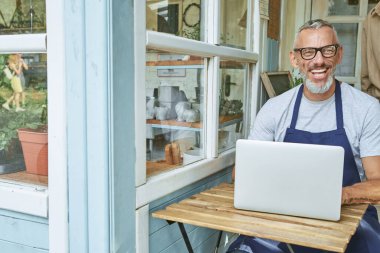 Bilgisayarda çalışan mutlu orta yaşlı beyaz adam.
