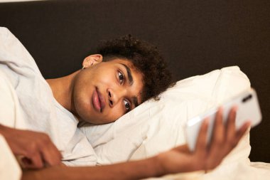 Yeni mesaj. Çekici esmer adamın portresini yakından çek. Evde yatakta uzanmış, dinleniyor ve akıllı telefon kullanıyor. Uyuyor.