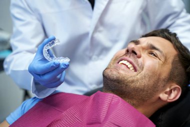 Erkek hastası için plastik diş kalıbı olan bir dişçi.