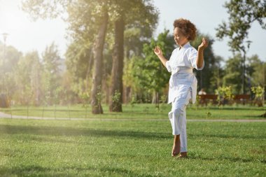 Kimonolu tatlı Afro-Amerikalı kız sokakta meditasyon yapıyor.