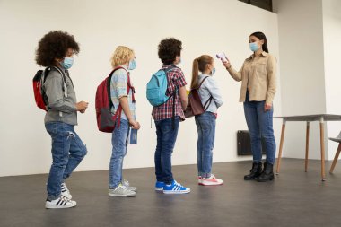 Koruyucu önlemler. Öğrenciler okula gelirken çocukların dijital termometreyle tarandığı uzun metrajlı bir resim.