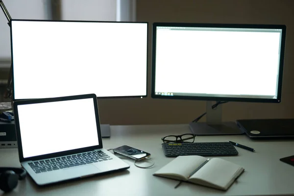 Muitos tela branca em branco de monitores de computador com acessórios e ferramentas de trabalho no espaço de trabalho freelance moderno — Fotografia de Stock