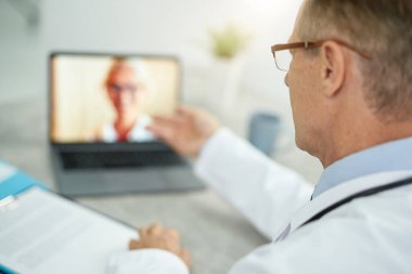 Klinikte online danışmanlık için dizüstü bilgisayar kullanan doktor