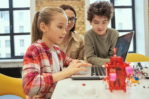 Understand how technology works. Cute little girl learn programming using laptop during STEM class together with young female teacher — Stock Photo, Image