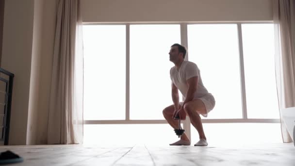 Stay healthy. Full length view of fit caucasian man wearing home clothes exercising, doing sit ups, holding dumbbell while working out at home — Video