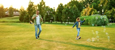 Genç babayla kızının güneşli bir günde sabun köpüğüyle eğlenip parkta vakit geçirdikleri uzun bir çekim.