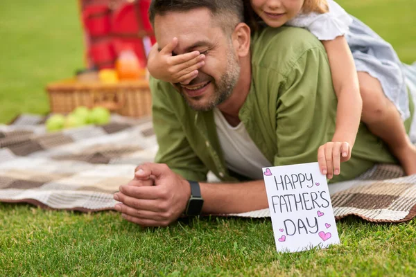 Cute little girl surprising her father, greeting and giving him handmade postcard, daddy and daughter celebrating Fathers Day in the park — Stock Photo, Image