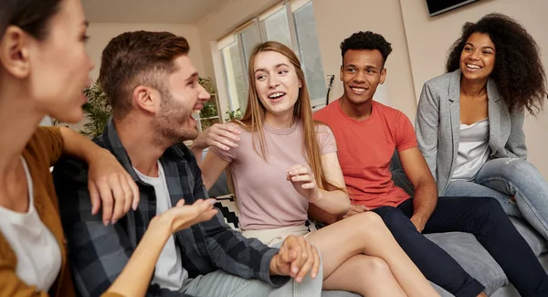 Happy moments. Group of young happy multicultural people in casual wear enjoying time together while sitting on the sofa in the modern apartment