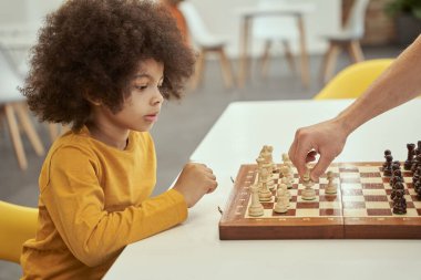Hevesli bir oyuncu. Yetişkinlerle satranç oynarken düşünen, kapalı bir masada oturan sevimli, zeki bir çocuk.