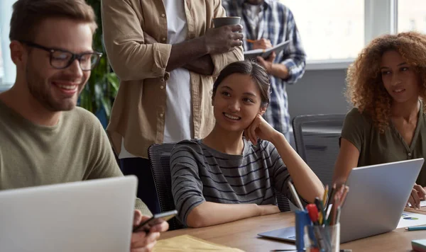 Jovens empresários multirraciais no trabalho. Feliz bela mulher asiática sorrindo enquanto se comunica com os colegas, gostando de trabalhar juntos no escritório moderno — Fotografia de Stock