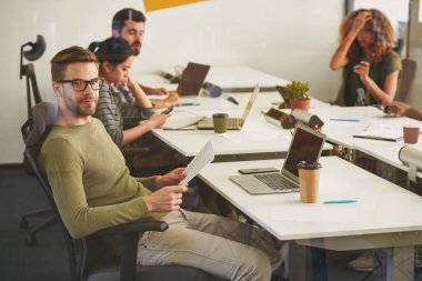 Sakin erkek ofis çalışanı iş yerinde poz veriyor.