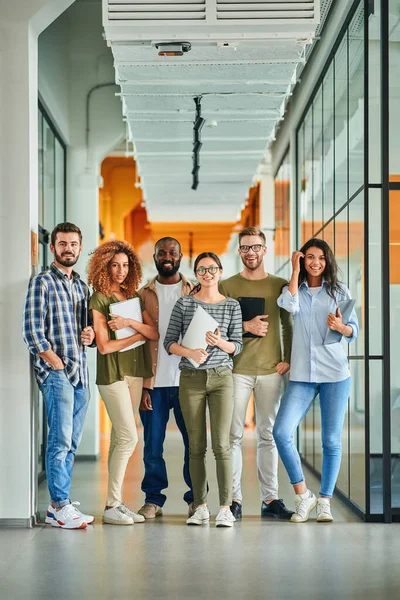 Sechs junge Leute lächeln und posieren mit Laptops in der Hand — Stockfoto