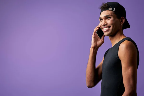 Retrato de homem morena transexual falando no celular em camiseta preta e boné. Sexo trans latino — Fotografia de Stock