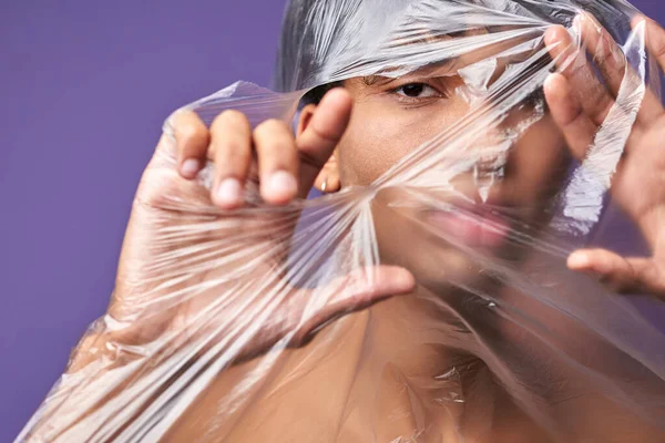 Közelíts meg egy vízszintes portrét egy fiatalemberről, aki szemekkel tépi szét a műanyag zacskót. Transznemű személyek szabadsága — Stock Fotó