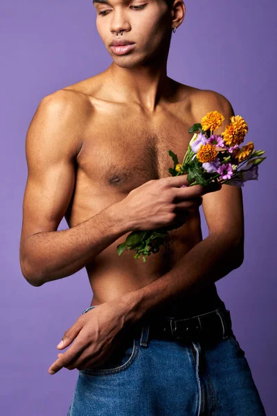 Sensitive transgender man with colorful flowers on purple background close up portrait shot. Muscular — Stock Photo, Image