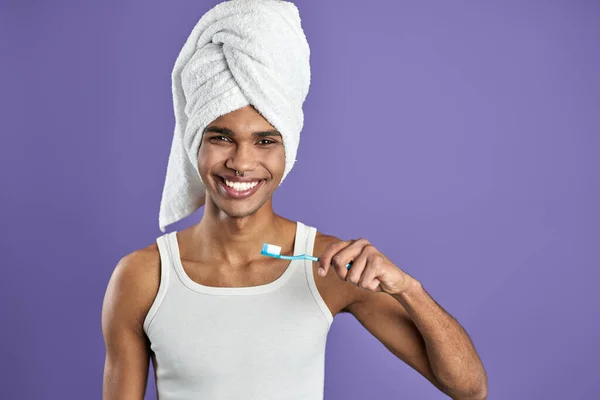 Joven hombre transgénero cepillándose los dientes aislados sobre fondo púrpura retrato — Foto de Stock