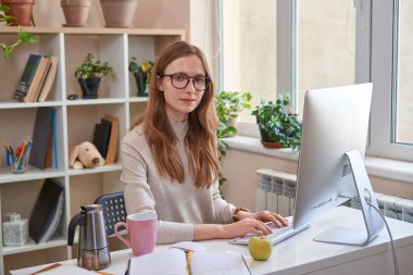 Gözlüklü genç bayan evde çalışıyor.