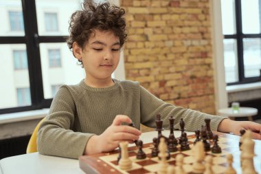 Sadece çal. Akıllı çocuk sınıfta oturuyor ve satranç oynarken bir hamle planlıyor.