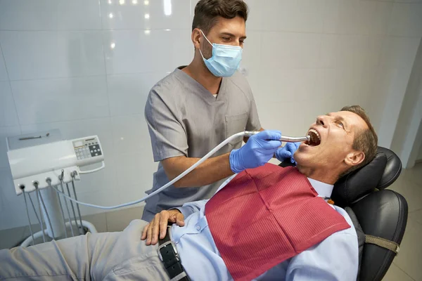 Mannelijke tandarts doet behandeling voor man in stoel — Stockfoto