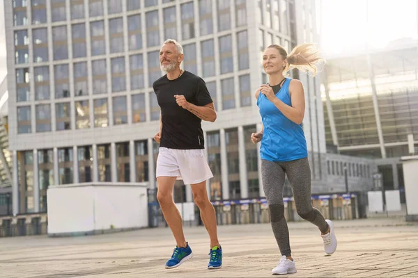 Aktif orta yaşlı çift, erkek ve kadın sabah antrenman yaparken birlikte koşuyorlar.