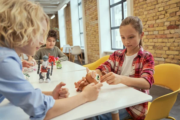 Független gondolkodás. Megfigyelő gyerekek ülnek az asztalnál, műszaki játékokat vizsgálnak, miközben időt töltenek a mérnöki klubban — Stock Fotó