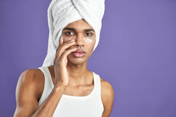 El joven afroamericano usa parches de gel en los ojos. Fondo púrpura aislado. Cosmetología de belleza procedimiento —  Fotos de Stock