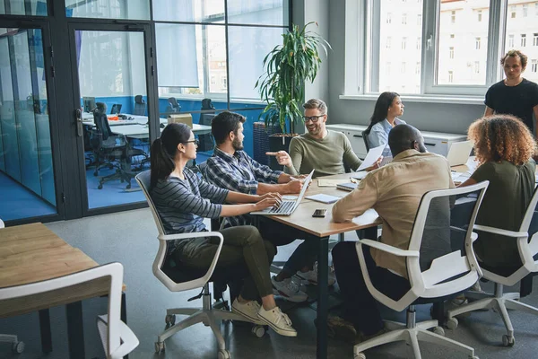 Focalizzato entusiasta giovane uomo e donne seduti al tavolo dell'ufficio — Foto Stock