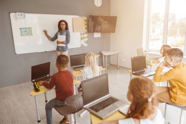 Sınıfta tahtaya yazı yazan Afro-Amerikan öğretmen.