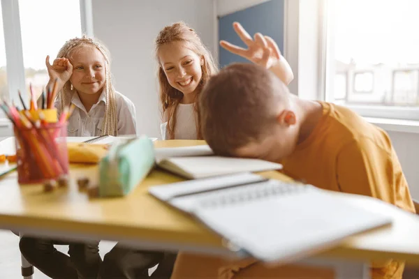 Glimlachende meisjes grappen naar hun klasgenoot in de klas — Stockfoto