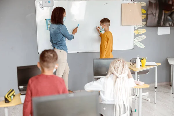 Nauczyciel i uczeń stojący przy tablicy w klasie — Zdjęcie stockowe