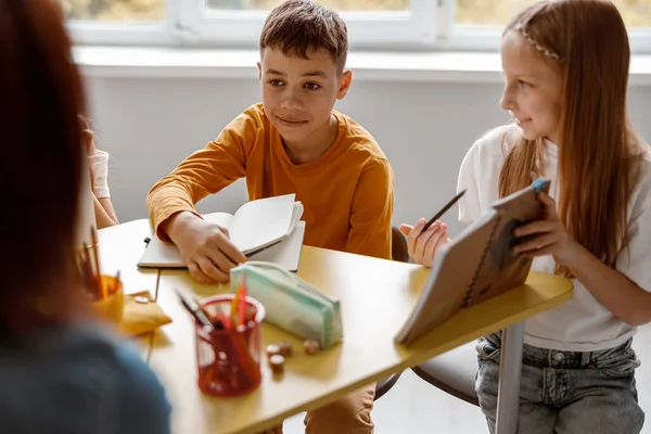 Усміхнені діти сидять за столом і використовують блокноти — стокове фото