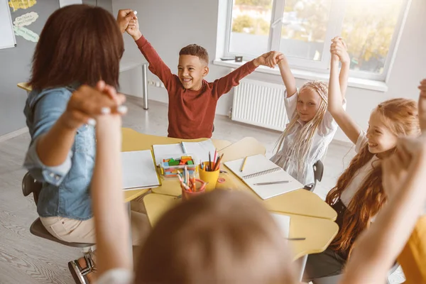 Barn som sitter vid bordet och sträcker upp händerna — Stockfoto