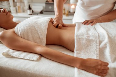 Kadın müşteri sağlık merkezinde mide masajı yaptırıyor.