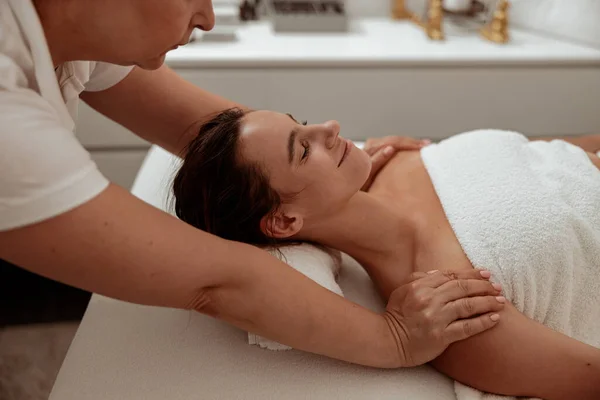 Mujer joven sonriente recibiendo masaje profesional en el salón de spa —  Fotos de Stock