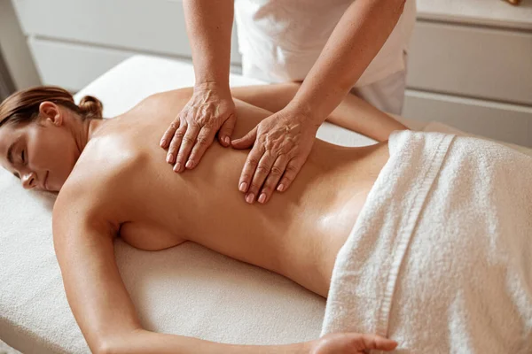 Encantadora mujer recibiendo masaje profesional en el salón de spa —  Fotos de Stock