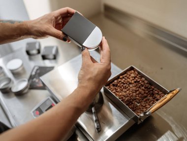 Erkek eli, metal kahve kavanozunu siyah kutuya koyar.